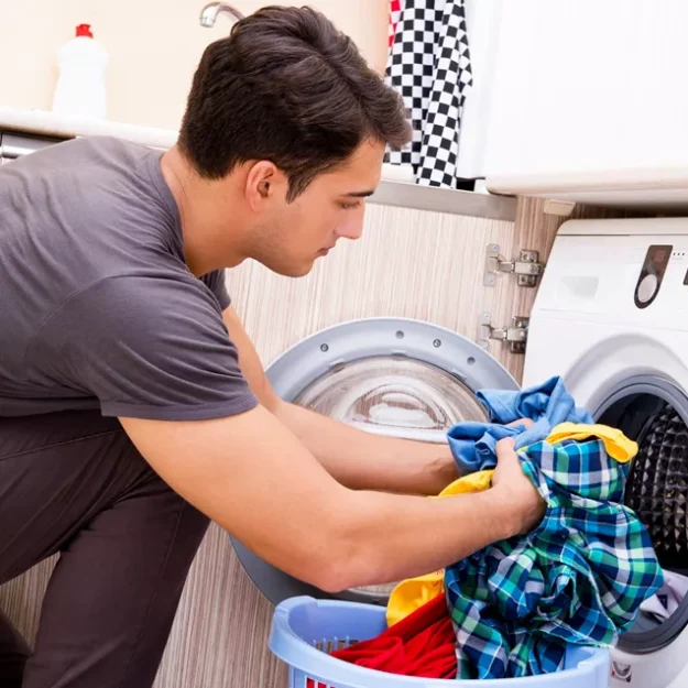 Young Man Loading The Washing Machine